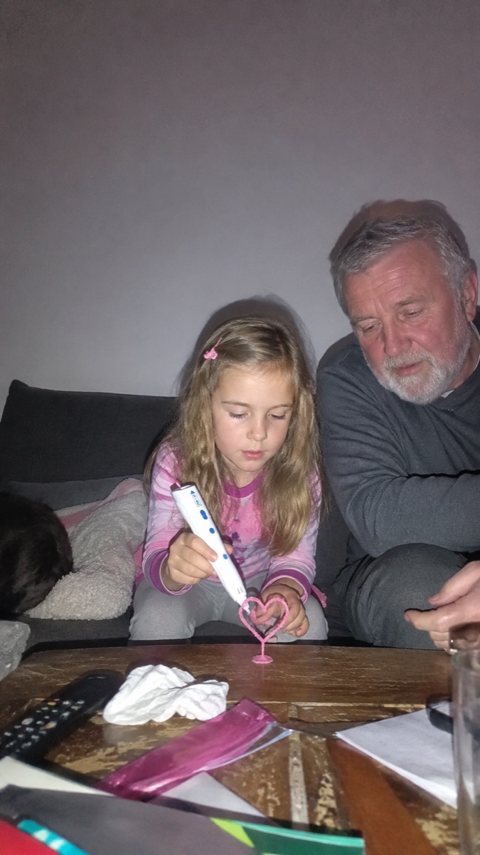 Una bambina sorride mentre tiene la penna 3D Pen'Up 3D e la sua creazione